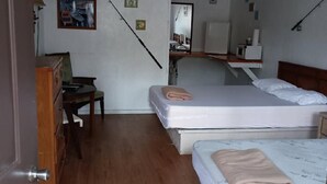 Un dormitorio con dos camas, un escritorio, una silla, un ventilador de techo y un espejo.