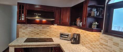 A kitchen with a granite countertop, a built-in oven, a toaster, and a coffee maker.