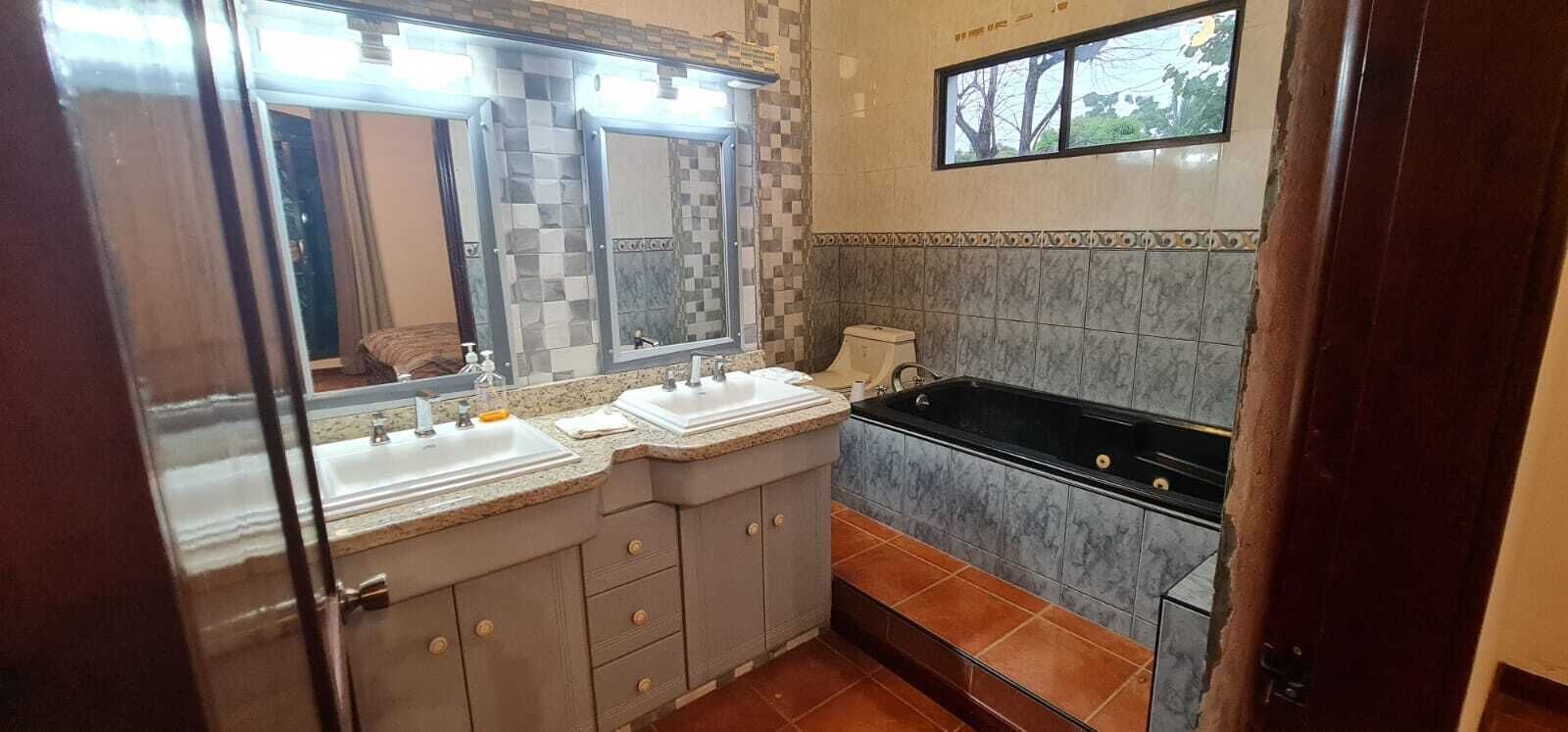 A bathroom with two sinks, a bathtub, and a large mirror.