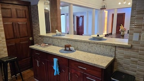 Een keuken met granieten aanrechtbladen, een grote spiegel en een houten deur.