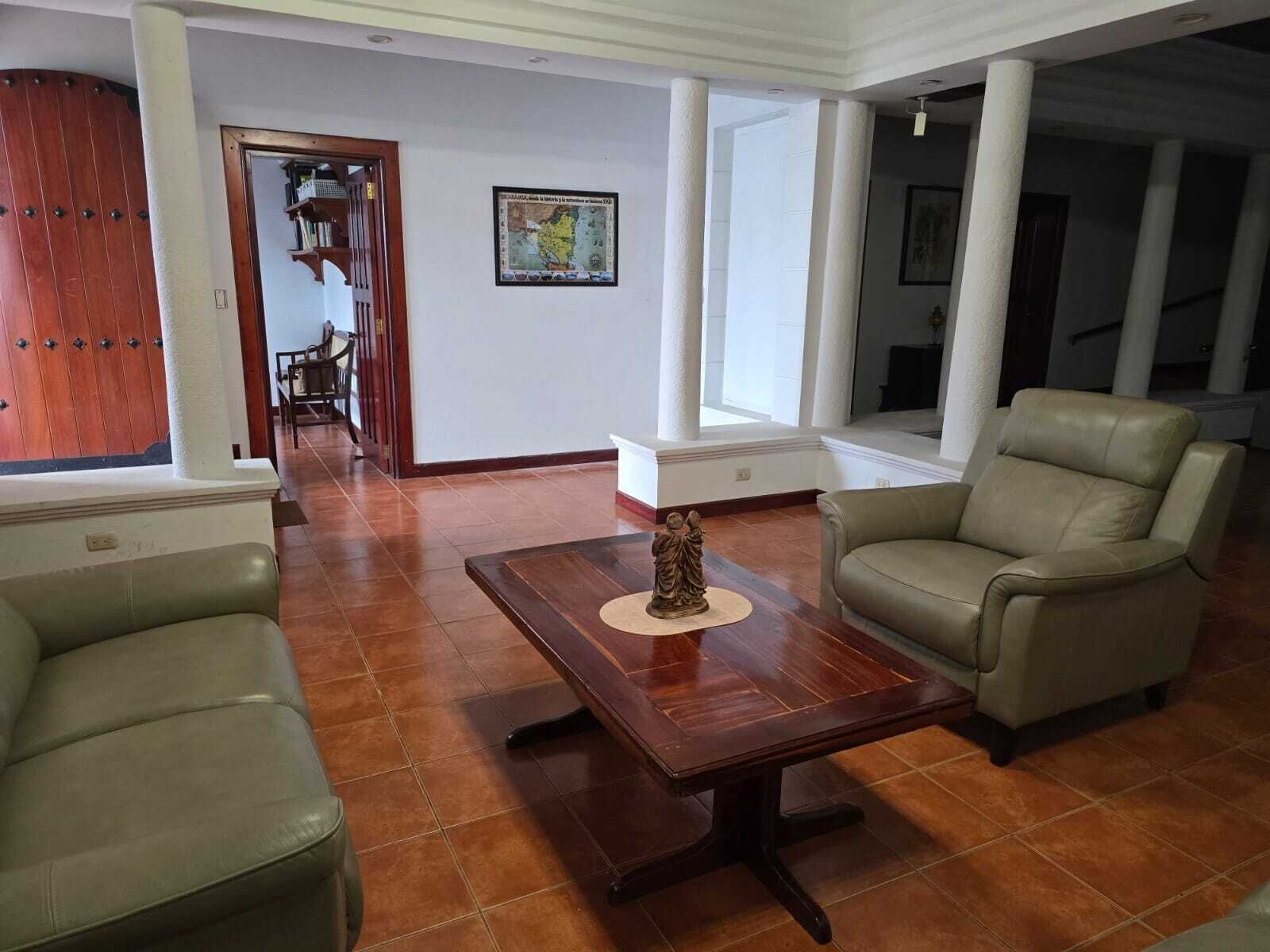 A spacious living room with a wooden coffee table, two leather armchairs, and a decorative statue.