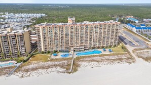 Een hoog hotel met meerdere balkons, een zwembad en een strandgedeelte.