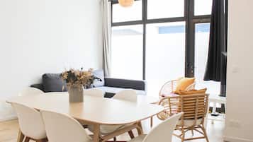 Un salon moderne comprenant une table à manger, des chaises, un canapé et un fauteuil en osier.