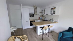 A compact kitchen with white cabinets, a wooden island, and bar stools. - Charming, quiet flat in Arcachon (Arcachon)