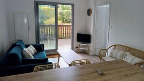 A living room with a sofa, a dining table, and a TV. - Charming, quiet flat in Arcachon (Arcachon)