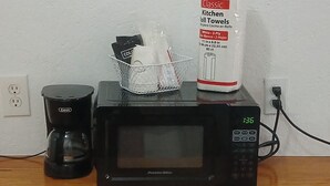 A Proctor stove top microwave on a wooden table with a coffee maker and a basket containing kitchen towels. - Cozy Hill Top 18 in welcoming Mayo with Wi-Fi, AC, fitness room (Mayo)