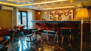 Un moderno vestíbulo de hotel con zona de bar, disposición de asientos y una pared decorativa.
