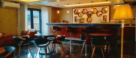 A modern hotel lobby with a bar area, seating arrangement, and a decorative wall.