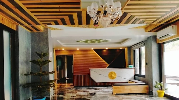 Un vestíbulo moderno con piso de mármol, techo de madera y una recepción con emblema dorado.