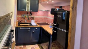 A kitchen with dark cabinets, a wooden countertop, and a black refrigerator. - Charming gîte in the heart of a water mill. 40 minutes from Le Mans and 15 minutes from Le Perche (Moncé-en-Saosnois)
