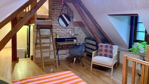 A cozy attic bedroom with exposed wooden beams, a loft bed, a desk, and a hanging light fixture. - Charming gîte in the heart of a water mill. 40 minutes from Le Mans and 15 minutes from Le Perche (Moncé-en-Saosnois)