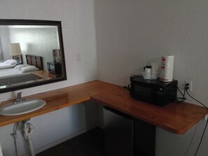 A hotel bathroom with a wooden vanity, a sink, a mirror, a microwave, and toiletries on the counter. - Charming Hill Top Room 17 in Mayo with WiFi, AC, fitness room (Mayo)