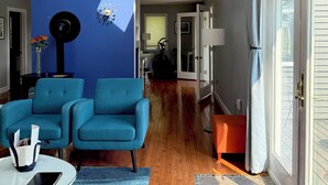 A modern living room with a blue wall, a ceiling fan, and a view to the outside.