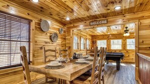A wooden interior with a dining table set for four, a pool table, and a 'WELCOME' sign. - Hidden Haven, Hot Tub, FREE Attraction tickets each paid day, Game Room, WIFI!!! (Sevierville)