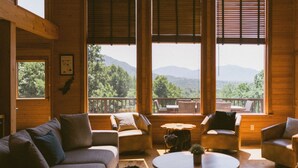 A cozy cabin interior with a sofa, armchairs, and a round table. Large windows offer a view of the outdoors. - Gorgeous Views. Resort-Style Amenities Await (Afton)
