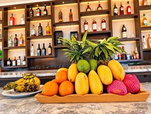 Una zona de bar con estantes llenos de botellas de licores y una exhibición de frutas.