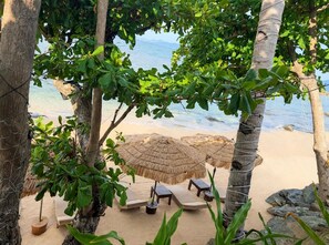 Une plage avec des parasols en chaume, des chaises longues et une vue sur la mer.