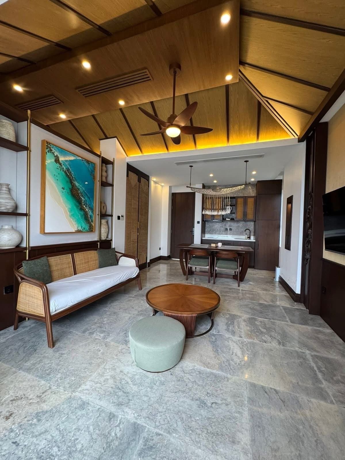 A modern living room with a sofa, round coffee table, and a dining area with a chandelier.