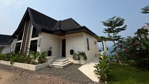 Una casa moderna de dos pisos con techo inclinado, un porche delantero y vista al mar.