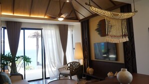 Una habitación con un ventanal grande, un ventilador de techo, un televisor y un adorno colgante.