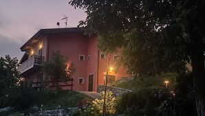 Un edificio rosa con un balcone, un muro in pietra e un vialetto che conduce all'ingresso.