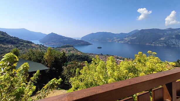 Panoramica di una zona costiera con montagne, un lago e un piccolo paese.