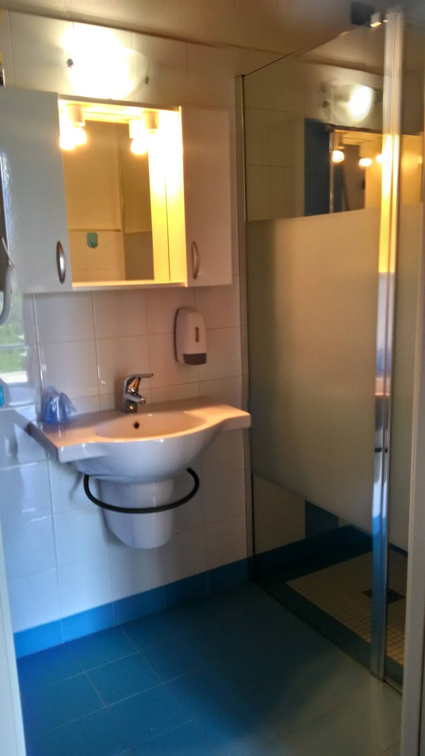 A bathroom with a sink, mirror, and a glass shower enclosure.