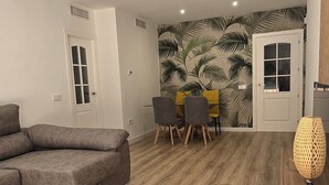 Una sala moderna con un sofá seccional gris, una mesa redonda de centro y un comedor con una silla amarilla.