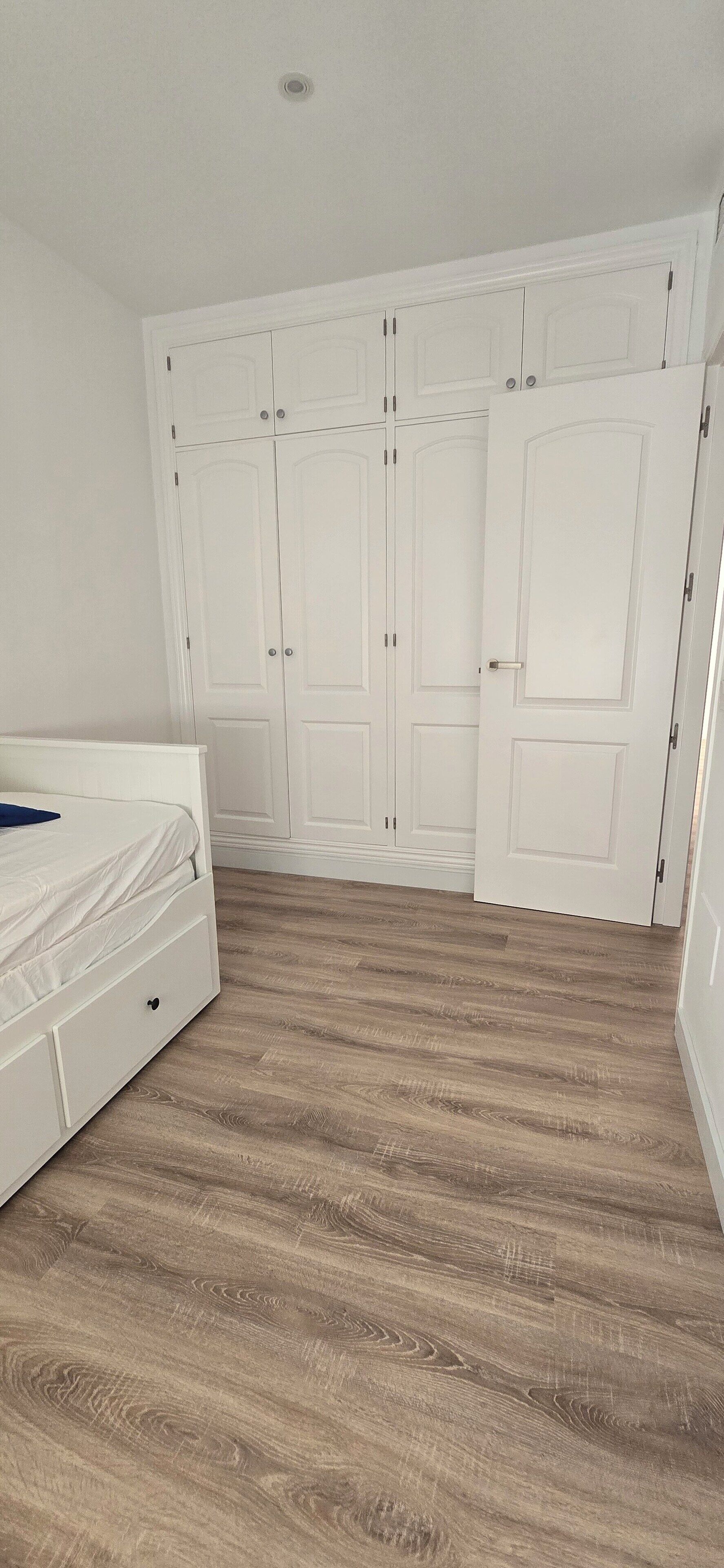 Una camera da letto con un letto, un armadio e un pavimento in legno.