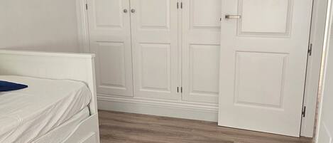 Una camera da letto con un letto, un armadio e un pavimento in legno.