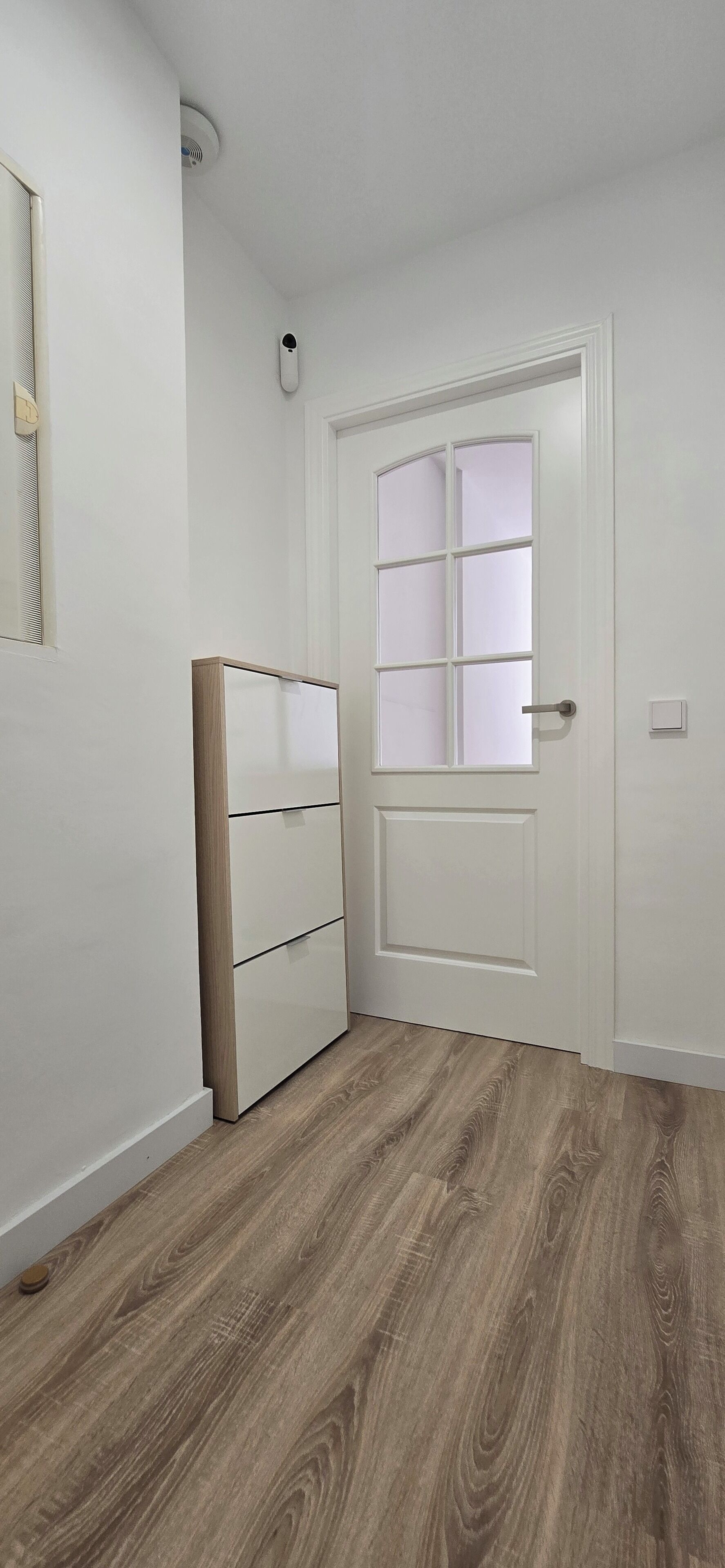 A room with a white door, a wooden floor, and a white wardrobe.