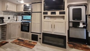 A compact kitchen with a microwave, oven, and built-in TV. - Cozy RV with terrific views, and peaceful surroundings. (Ukiah)