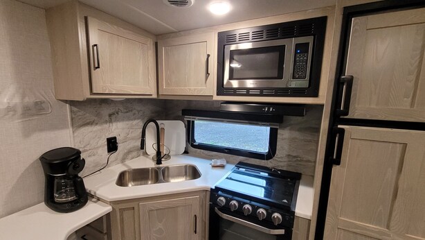 A compact kitchenette with a microwave, oven, sink, and coffee maker. - Cozy RV with terrific views, and peaceful surroundings. (Ukiah)