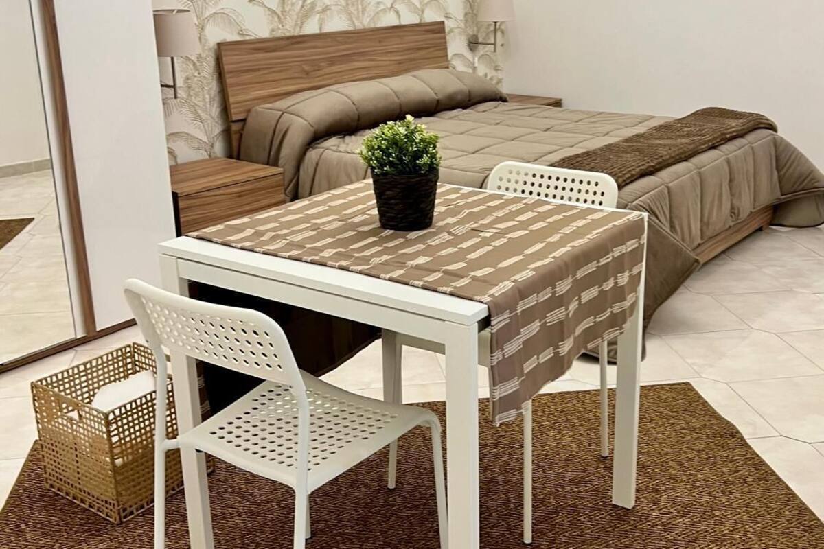 Un dormitorio con cama, mesita de noche, lámpara y un cuadro en la pared.