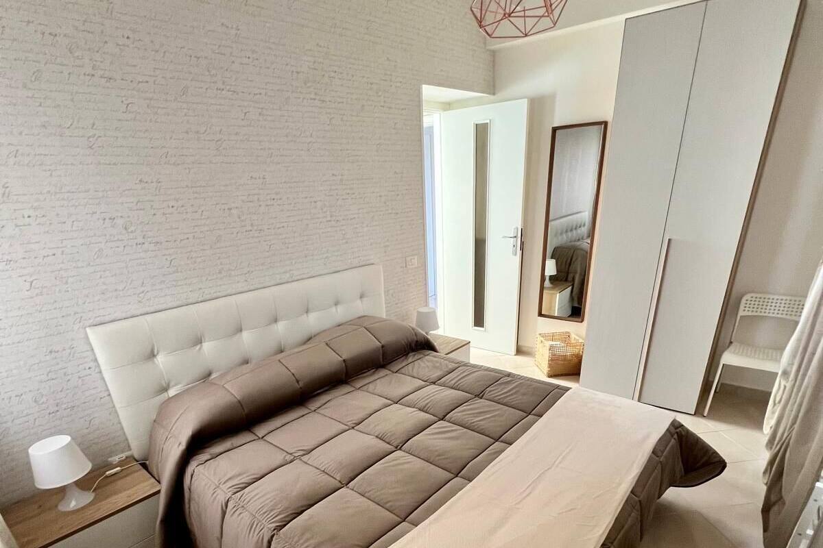 Un dormitorio moderno con una cama grande, una mesita de noche, una lámpara colgante y un armario.