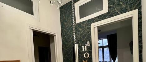 A hallway with a chandelier, a door with a 'HOME' sign, and a view into a dining area.