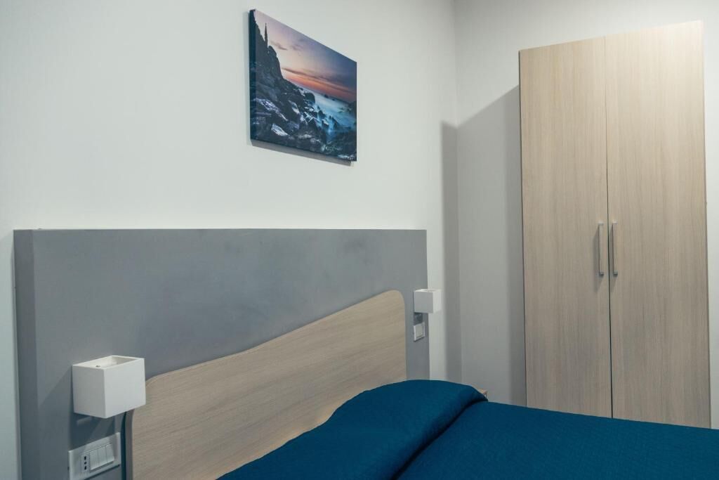 Une chambre à coucher comprenant un lit, une armoire, une lampe fixée au mur et un tableau.