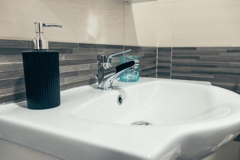 Un lavabo de salle de bain doté d’un robinet moderne et d’un distributeur de savon.