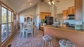 A spacious kitchen with wooden cabinets, a central island, and a dining area with chairs.