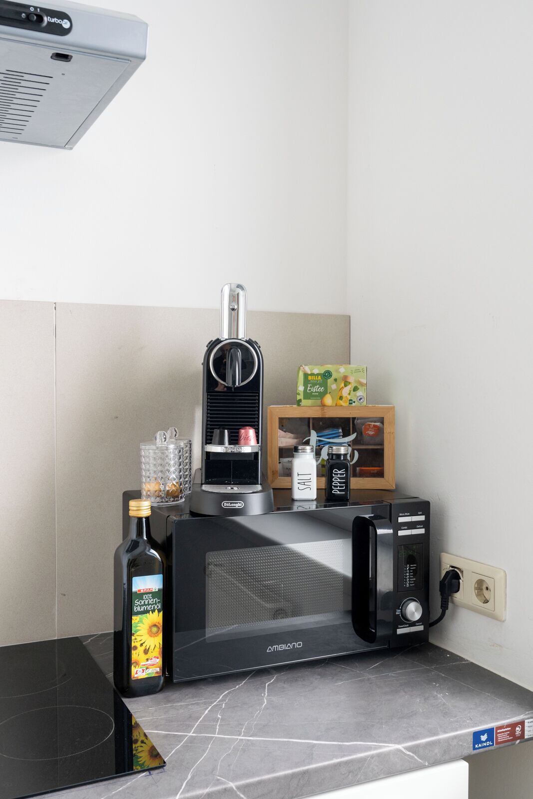 A kitchen with a microwave, coffee maker, and a bottle of sunflower oil.