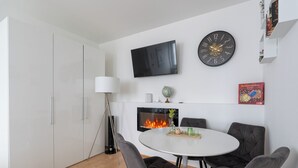 Un salon moderne avec une cheminée, une table ronde et une horloge au mur.