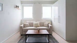 Un salon moderne et minimaliste, avec un canapé, une table basse et deux fenêtres.