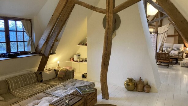 A cozy loft bedroom with a sloped ceiling, a sofa, a coffee table, and a dining area with a chair and table. - La LongeMer: Countryside & Sea Just a few kilometers from Veules-Les-Roses (Angiens)
