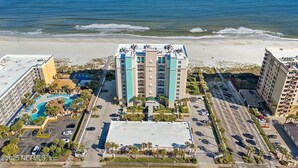 Ein Strandhotel mit mehreren Gebäuden, einem Schwimmbad und einem Parkplatz.