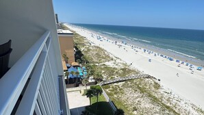 Ein Poolbereich mit Liegestühlen und Blick auf den Strand.