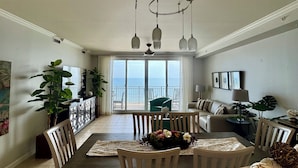 Ein großzügiges Wohnzimmer mit Essbereich, großen Fenstern und Meerblick.