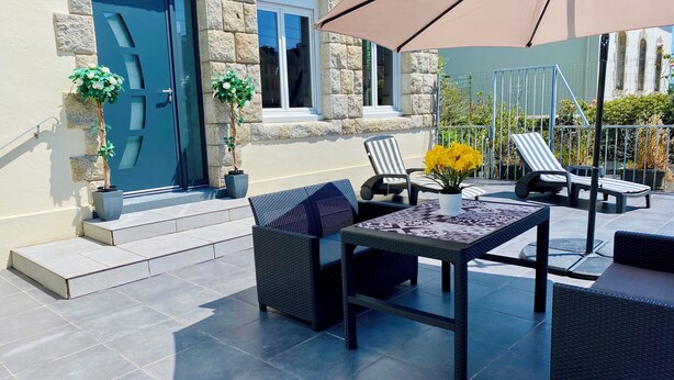 An outdoor patio with a table, chairs, and a large umbrella. - Spacious townhouse - 2 self-contained apartments for flexible living (Quimperlé)