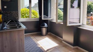 A kitchen with a modern design, featuring a large window, a built-in sink, and a trash bin. - Spacious townhouse - 2 self-contained apartments for flexible living (Quimperlé)