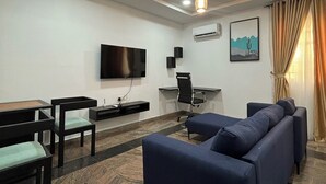 Un soggiorno moderno con un divano, poltrone, una TV e una scrivania.
