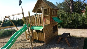 A wooden playhouse with a slide, climbing wall, and a small bench. - Mas Picton, 4 bedroom house with swimming pool, 10 min from the beach (Argelès-sur-Mer)